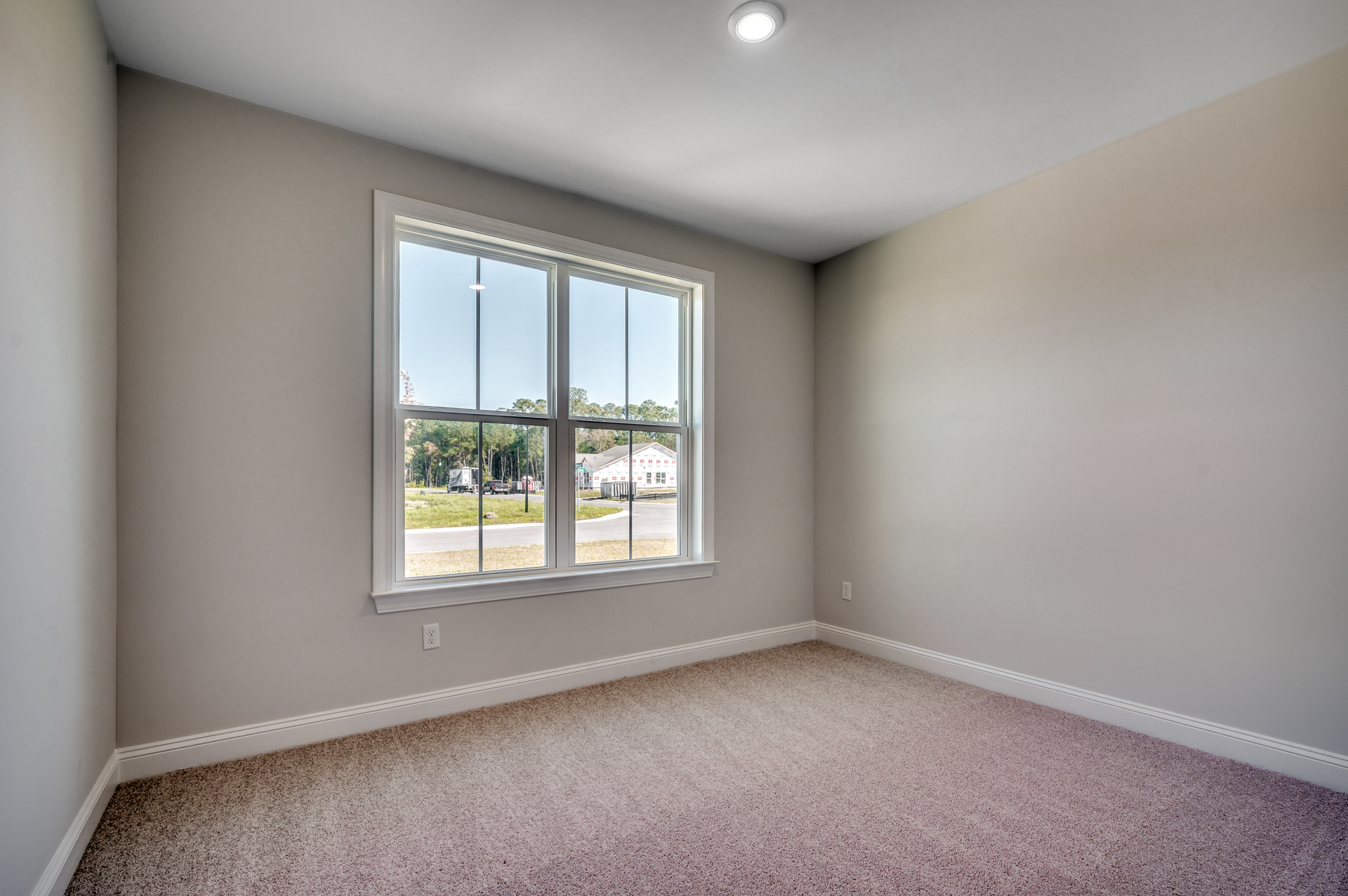 spacious room with large windows for natural lighting, light gray walls and carpeting throughout 