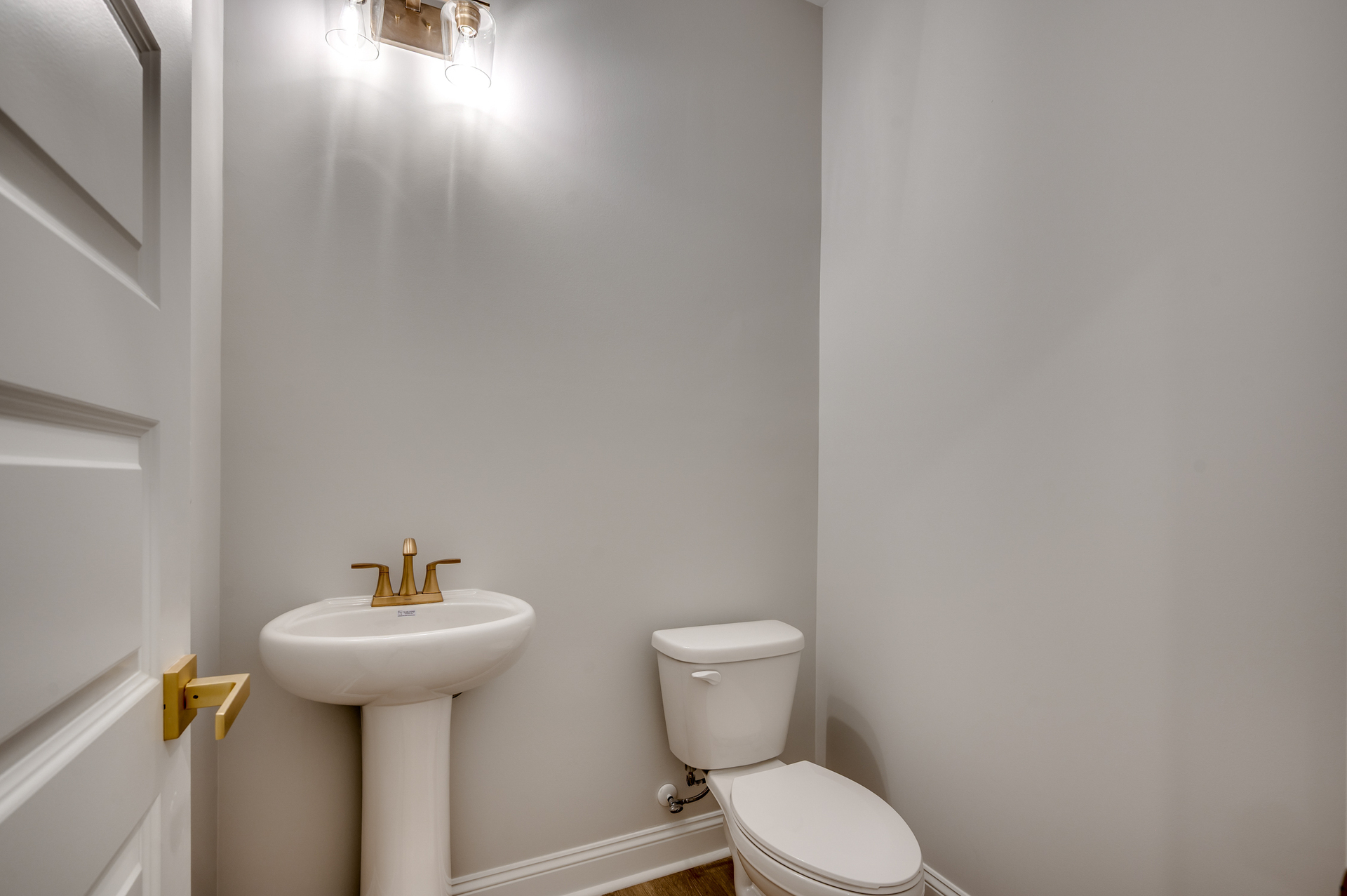 cozy space with light gray walls, single sink vanity and gold hardware 