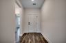 spacious hallway with bright white front door and dark brown hardwood flooring throughout 