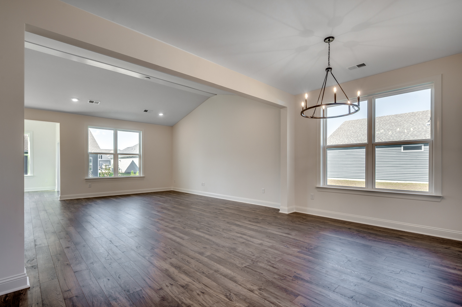 open-concept area with large chandelier, tan walls and dark hardwood flooring throughout