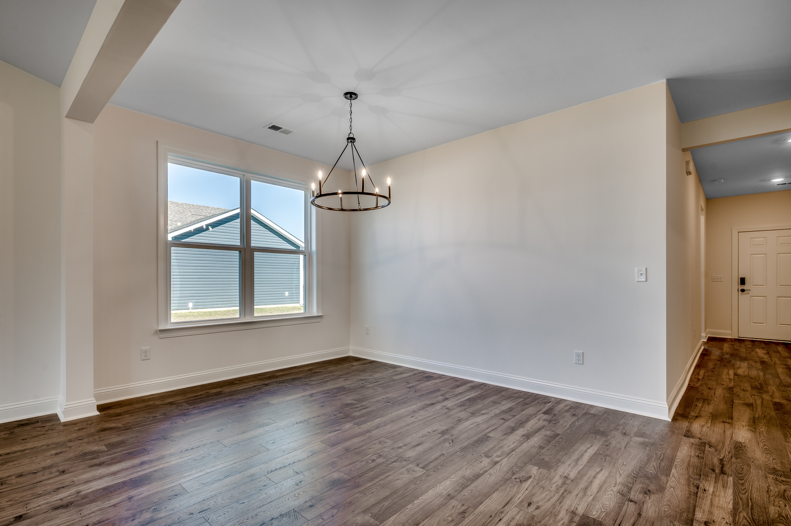 spacious area with large windows for natural lighting, dark hardwood flooring and large chandelier