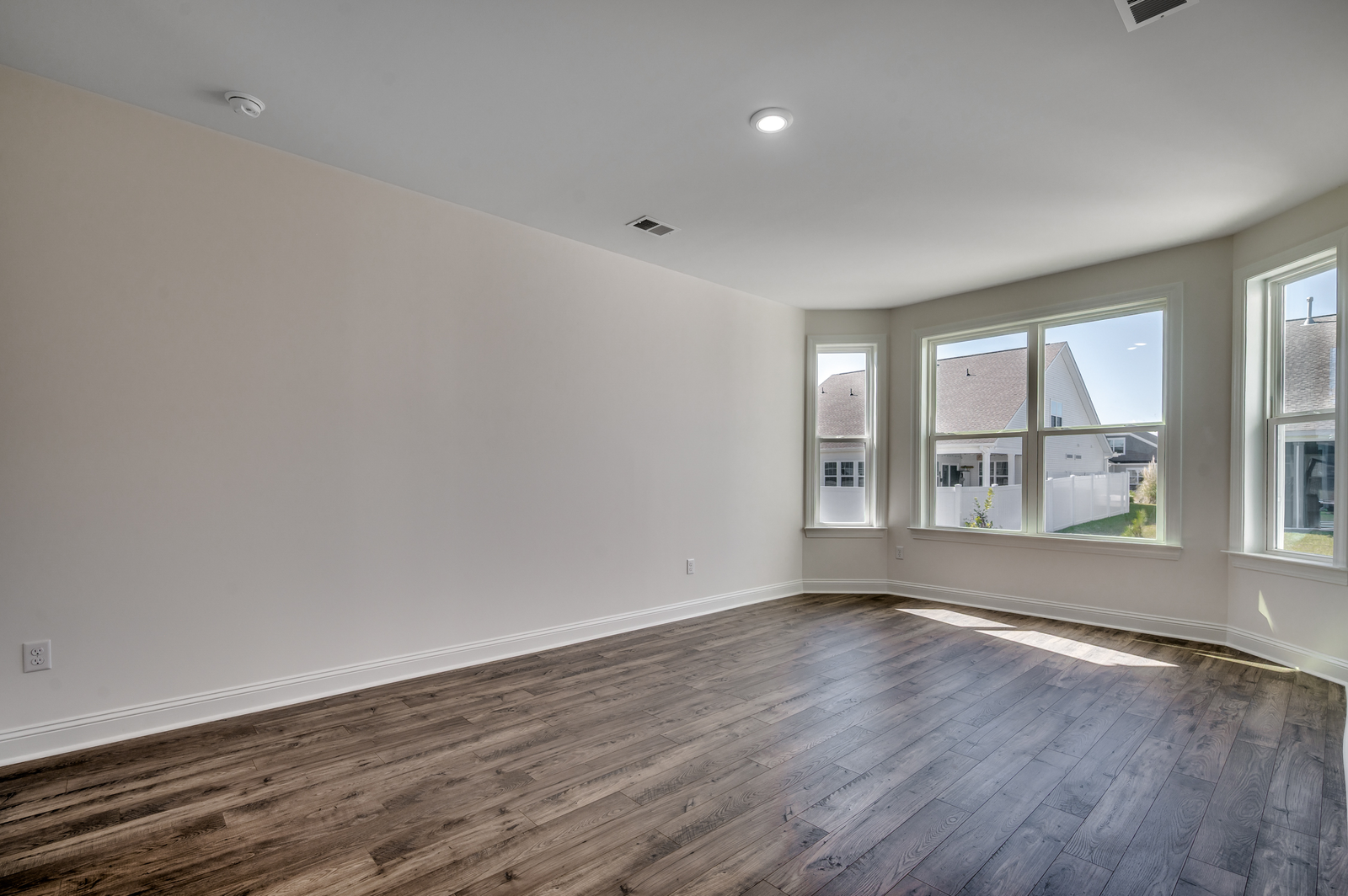 spacious room with large bay windows and hardwood flooring throughout