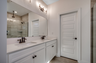 bright white dual vanity with large mirror and tile flooring throughout 