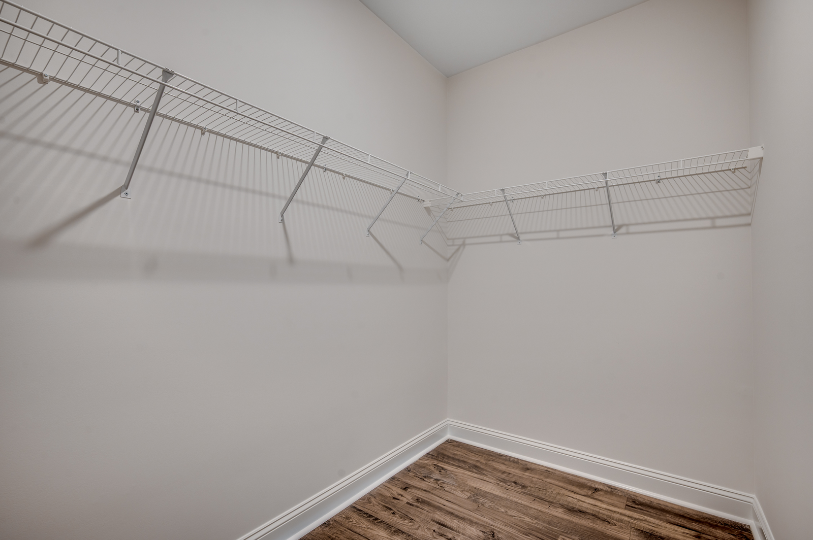 large walk-in closet with hardwood flooring and white wire shelving for additional storage
