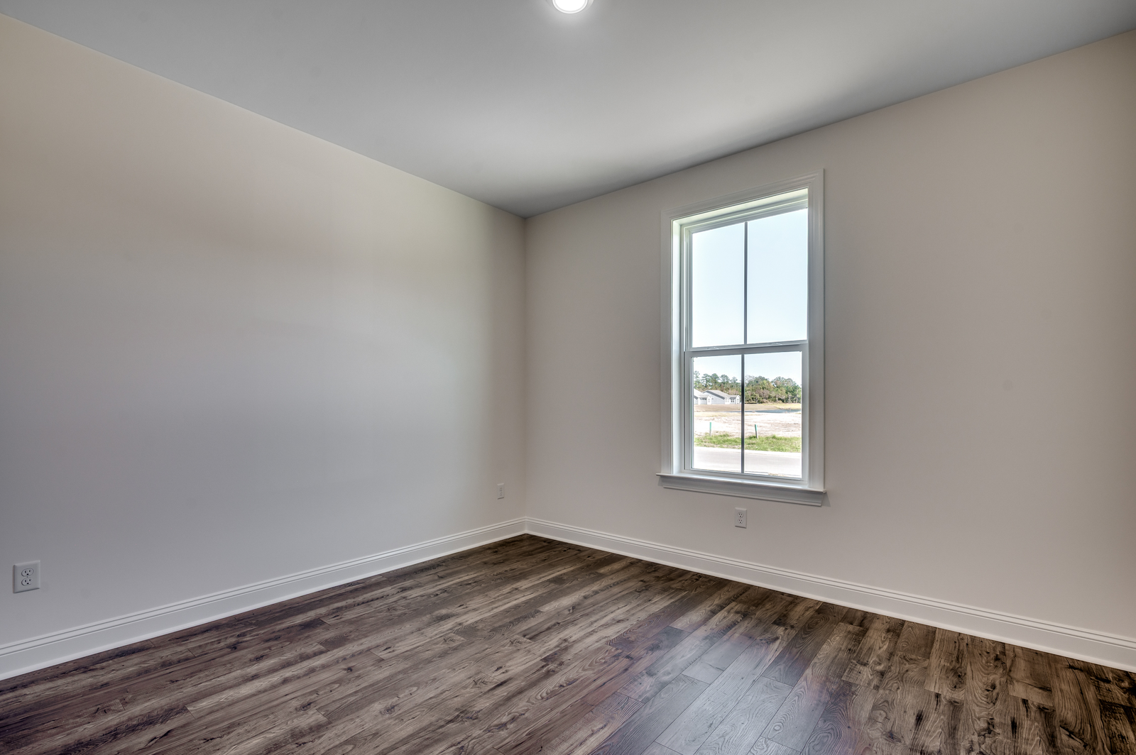spacious room with tan walls and dark brown hardwood flooring throughout
