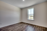 spacious room with tan walls and dark brown hardwood flooring throughout 