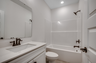 bright white bathroom with single sink vanity and black fixtures throughout 