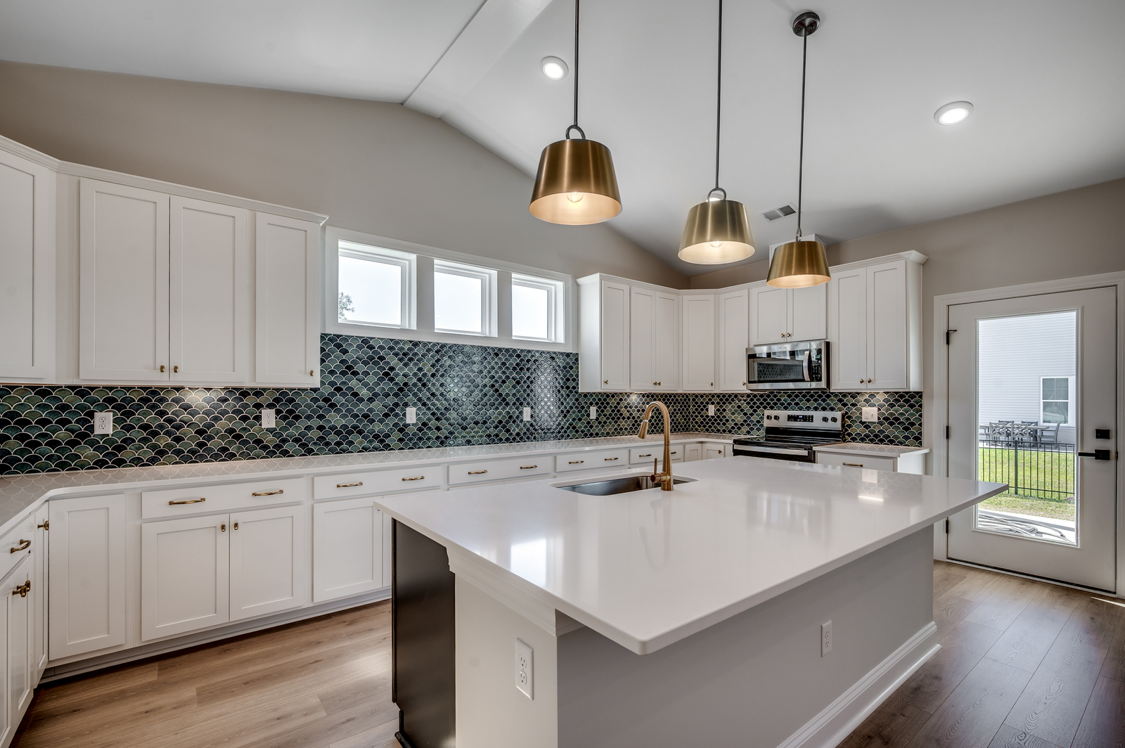 bright white cabinets with large island, gold fixtures and blue tiled backsplash