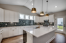 bright white cabinets with large island, gold fixtures and blue tiled backsplash 