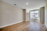 spacious room with light hardwood flooring and large windows filling the room with natural light 