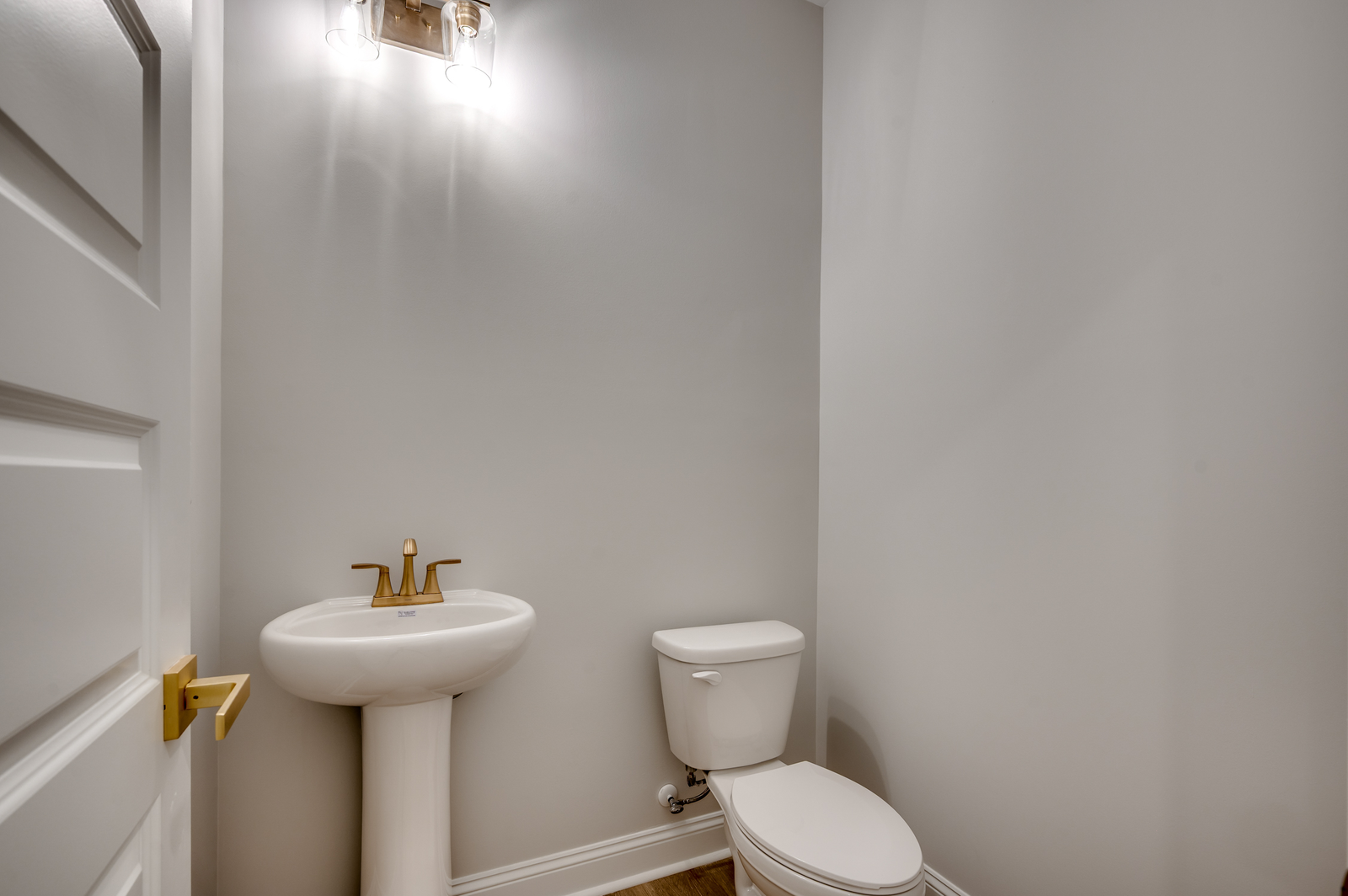 cozy space with light gray walls, single sink vanity and gold hardware