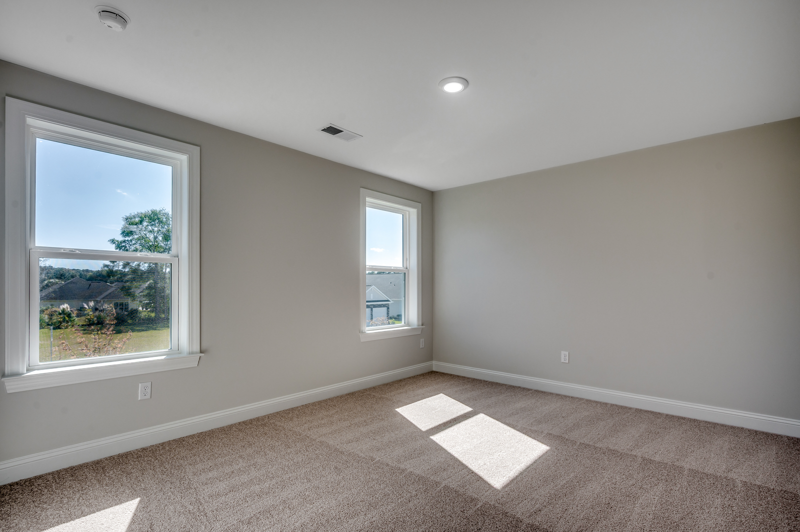 spacious room on second floor with two large windows for natural lighting and carpeting throughout