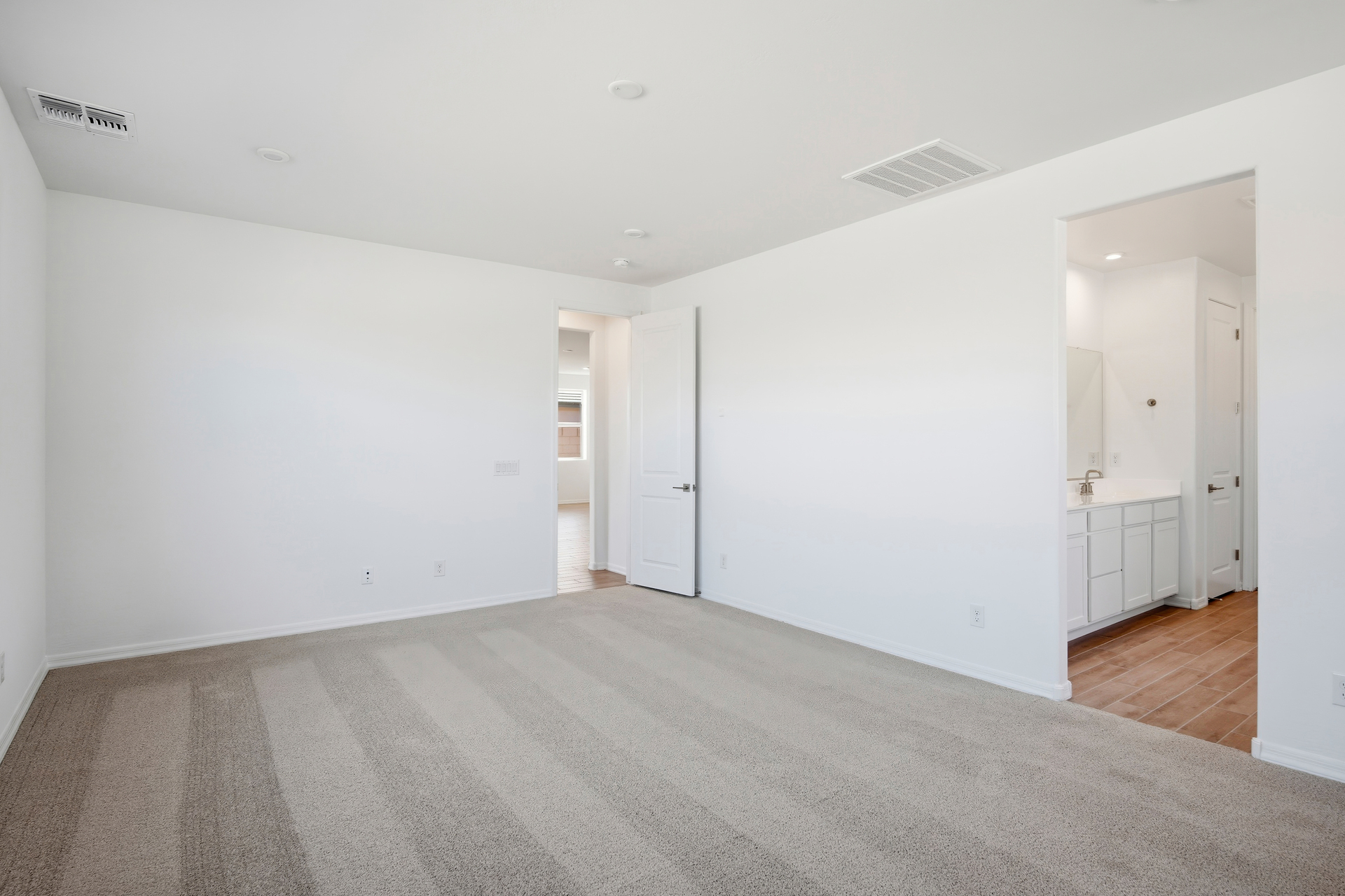 spacious bedroom with light brown carpet and plenty of natural light
