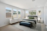 spacious bedroom with a king-sized bed, teal bed bench, and modern white nightstands