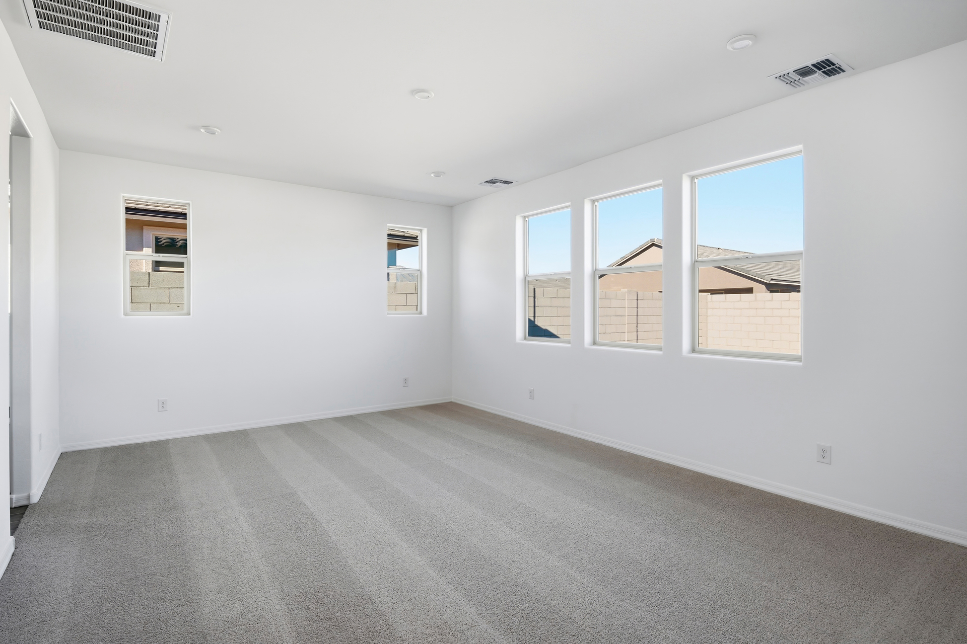 spacious bedroom with light brown carpet and plenty of natural light