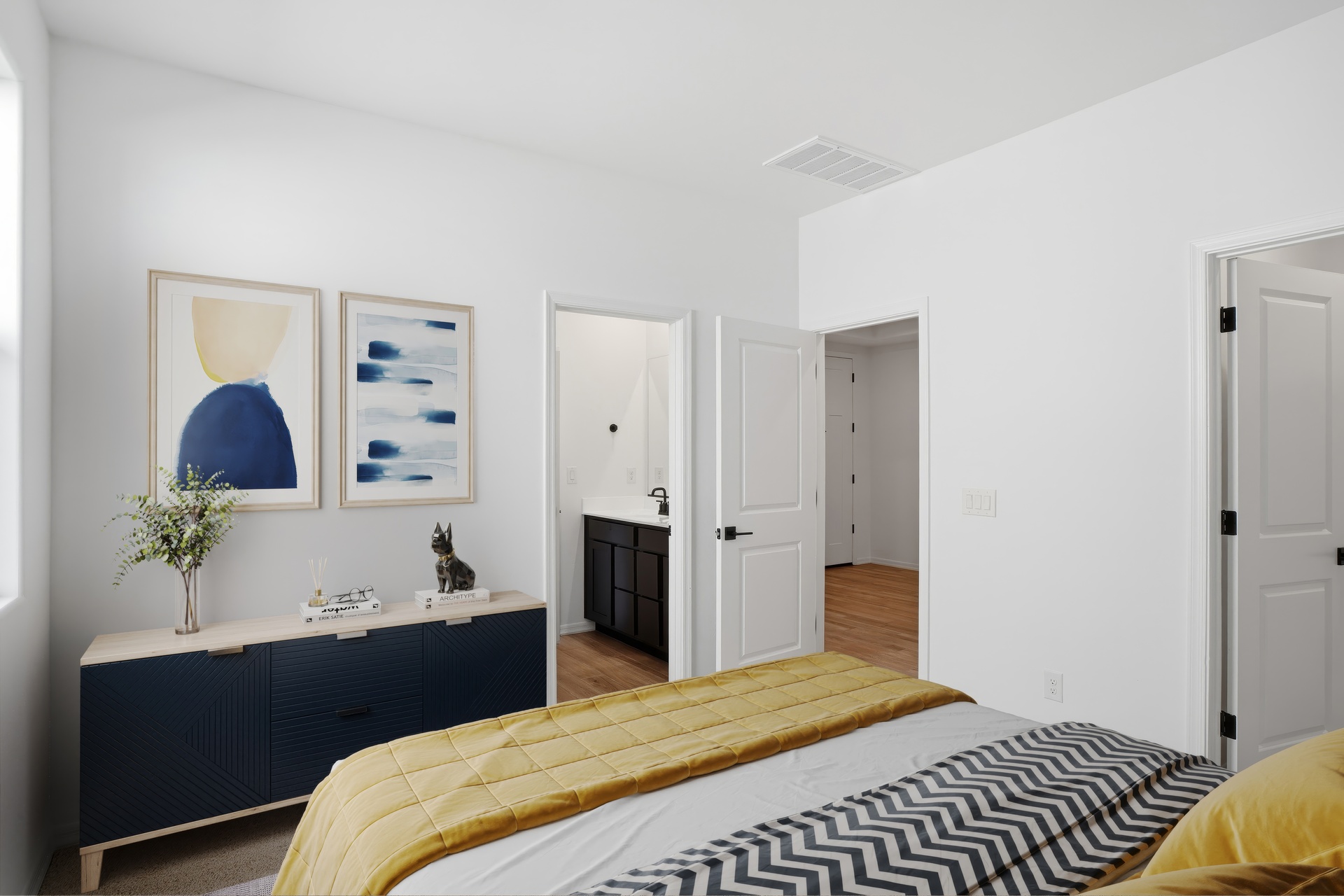 large bed with yellow duvet cover, wooden dresser, and yellow decorative pillows