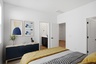 large bed with yellow duvet cover, wooden dresser, and yellow decorative pillows