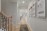 entryway with light wood floors, study with blue accent wall, and wood stairs with oak railing