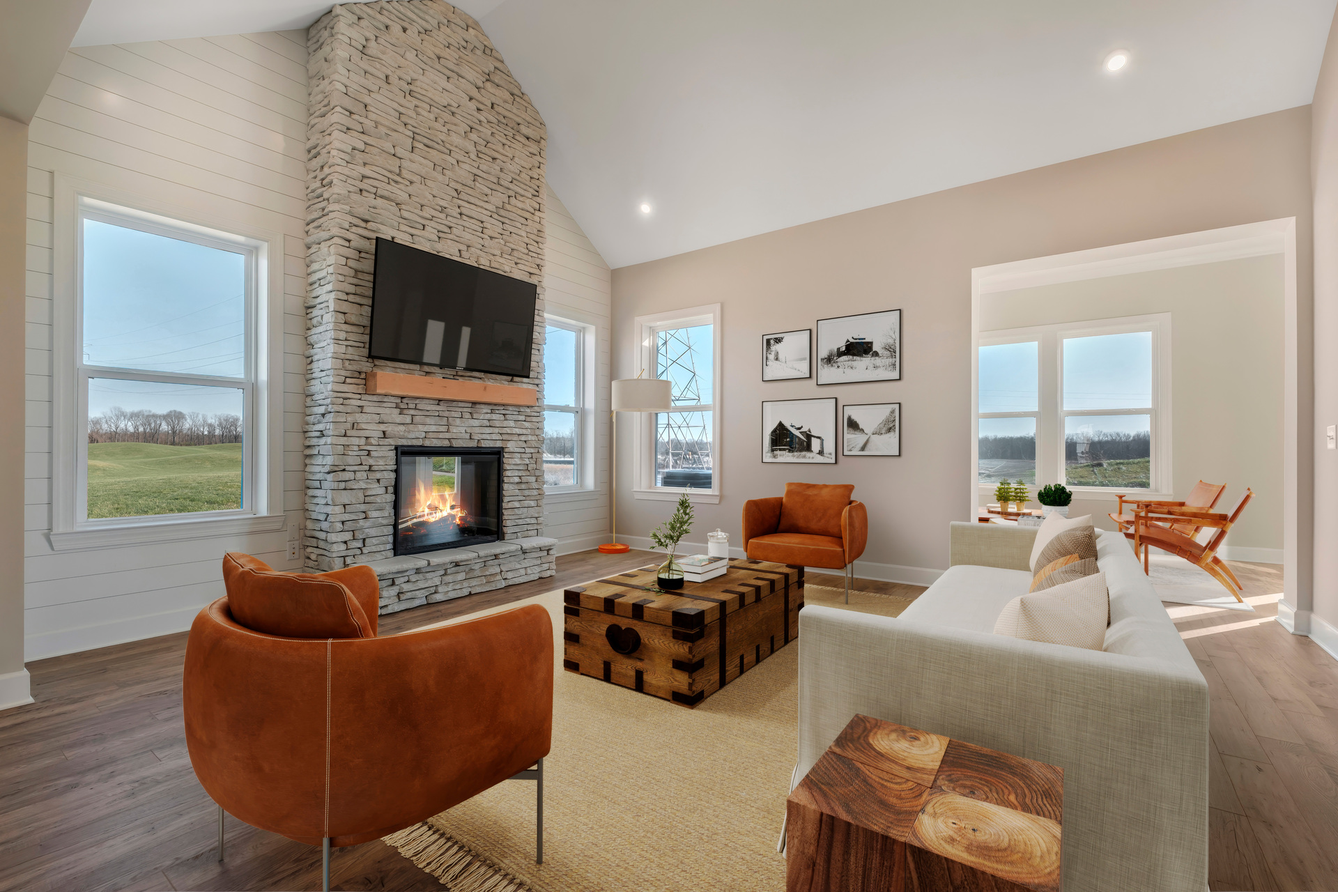 great room with wood floors, a stone fireplace, and vaulted ceilings