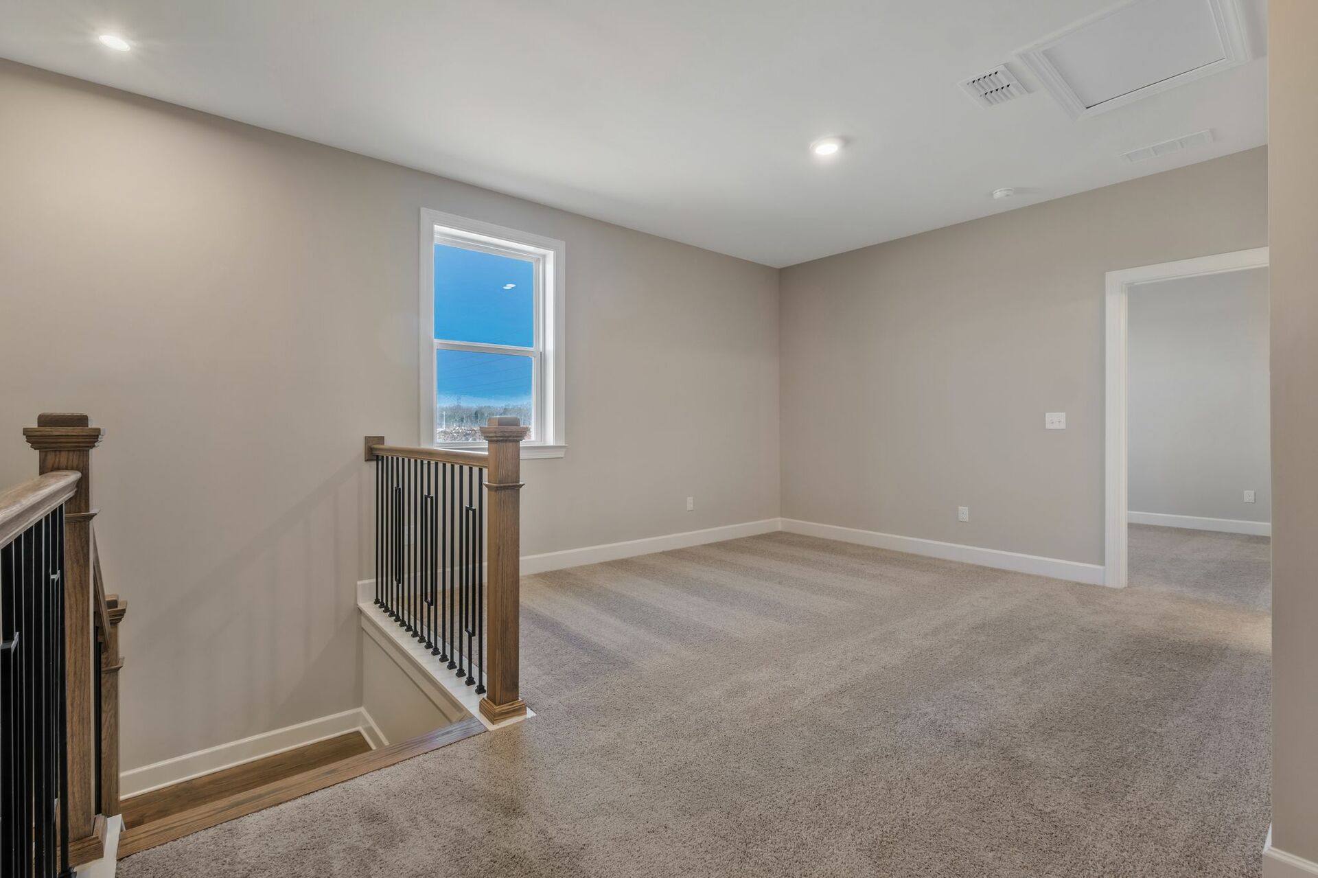 loft space with carpet flooring, white trim, and a view of the staircase