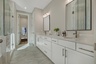 primary bathroom with a double sink vanity, glass shower, and white cabinets 