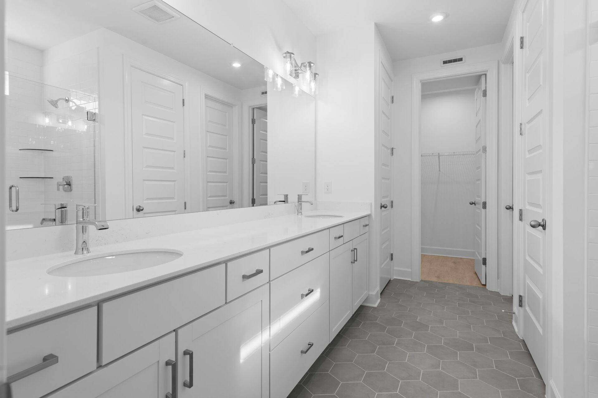 primary bathroom with white cabinets and white countertops