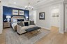 primary bedroom with blue accent wall and tray ceiling
