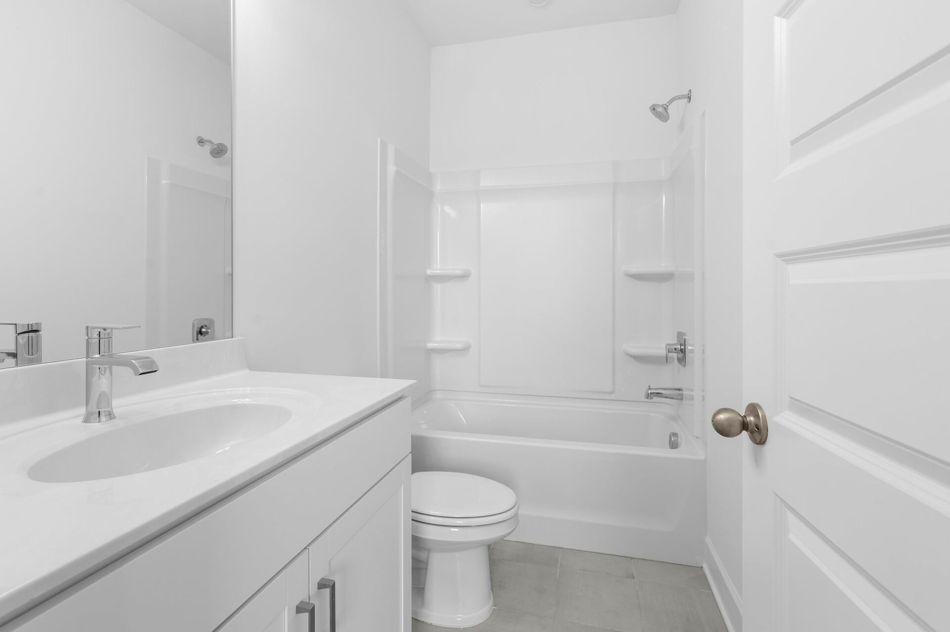secondary bathroom white countertops, white cabinets, and a shower and tub combination