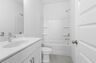 secondary bathroom white countertops, white cabinets, and a shower and tub combination