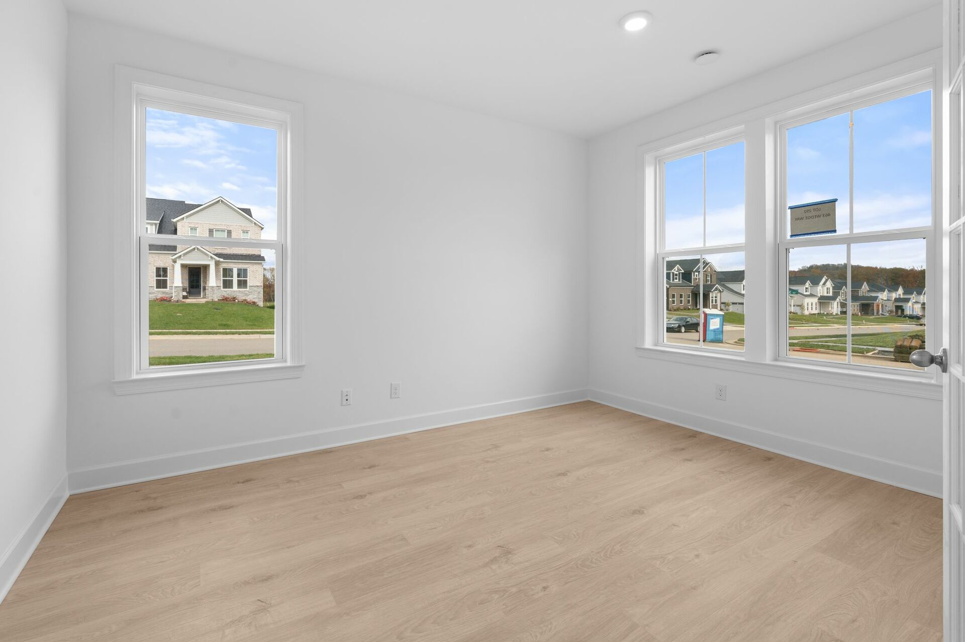 study with wood flooring, white trim, and large windows