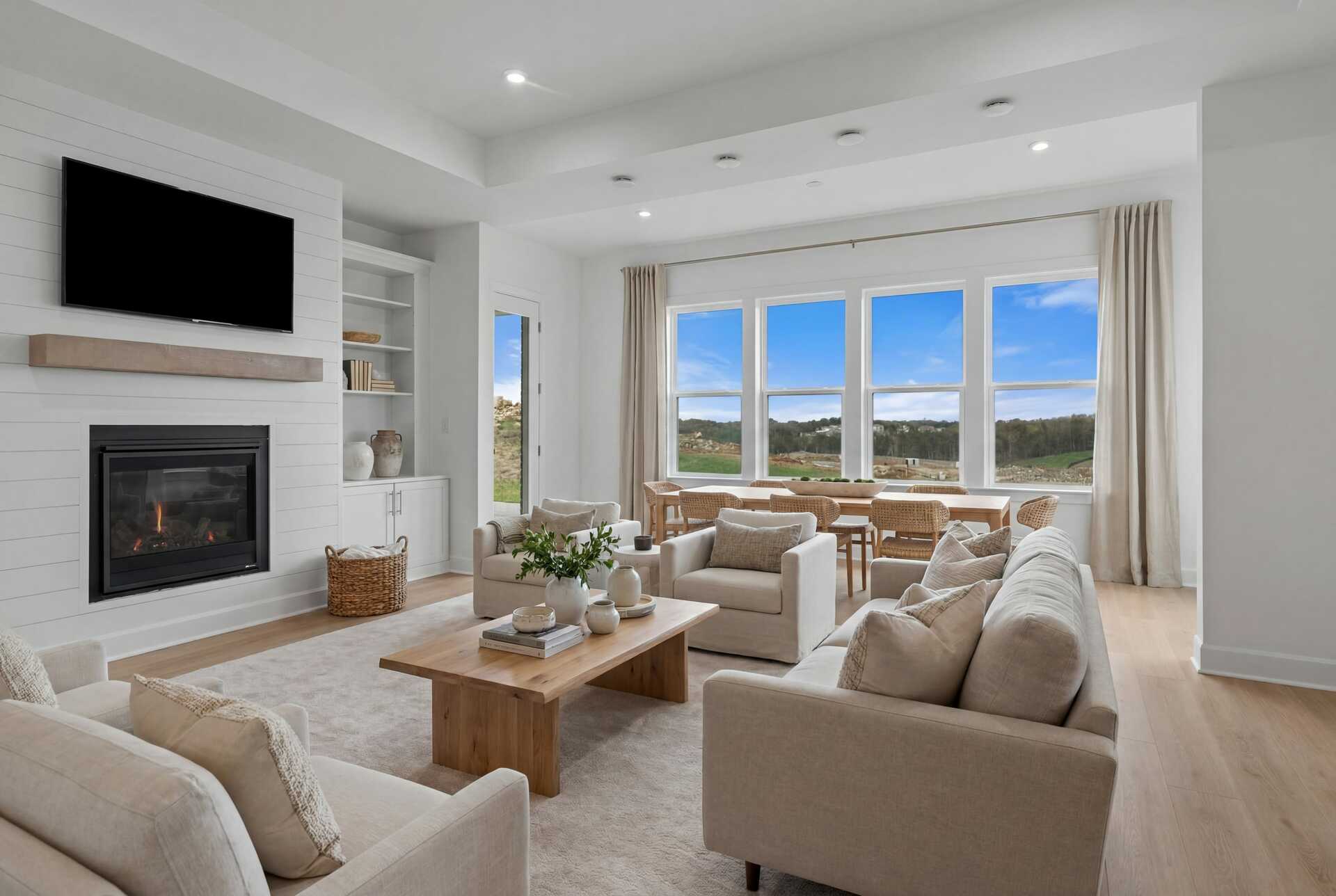 great room with wood flooring, shiplap fireplace, sofas, and a view of the dining room