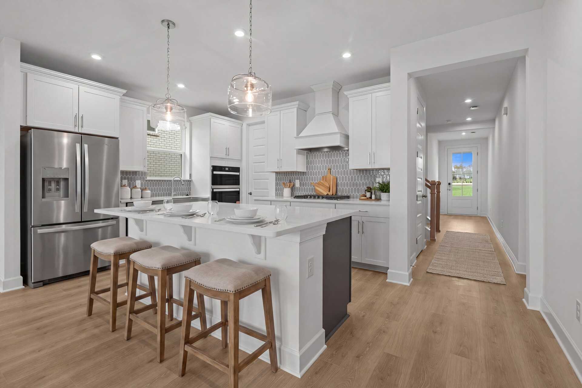 kitchen with wood flooring, white cabinets, white countertops, barstools and a view of the entryway