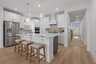 kitchen with wood flooring, white cabinets, white countertops, barstools and a view of the entryway