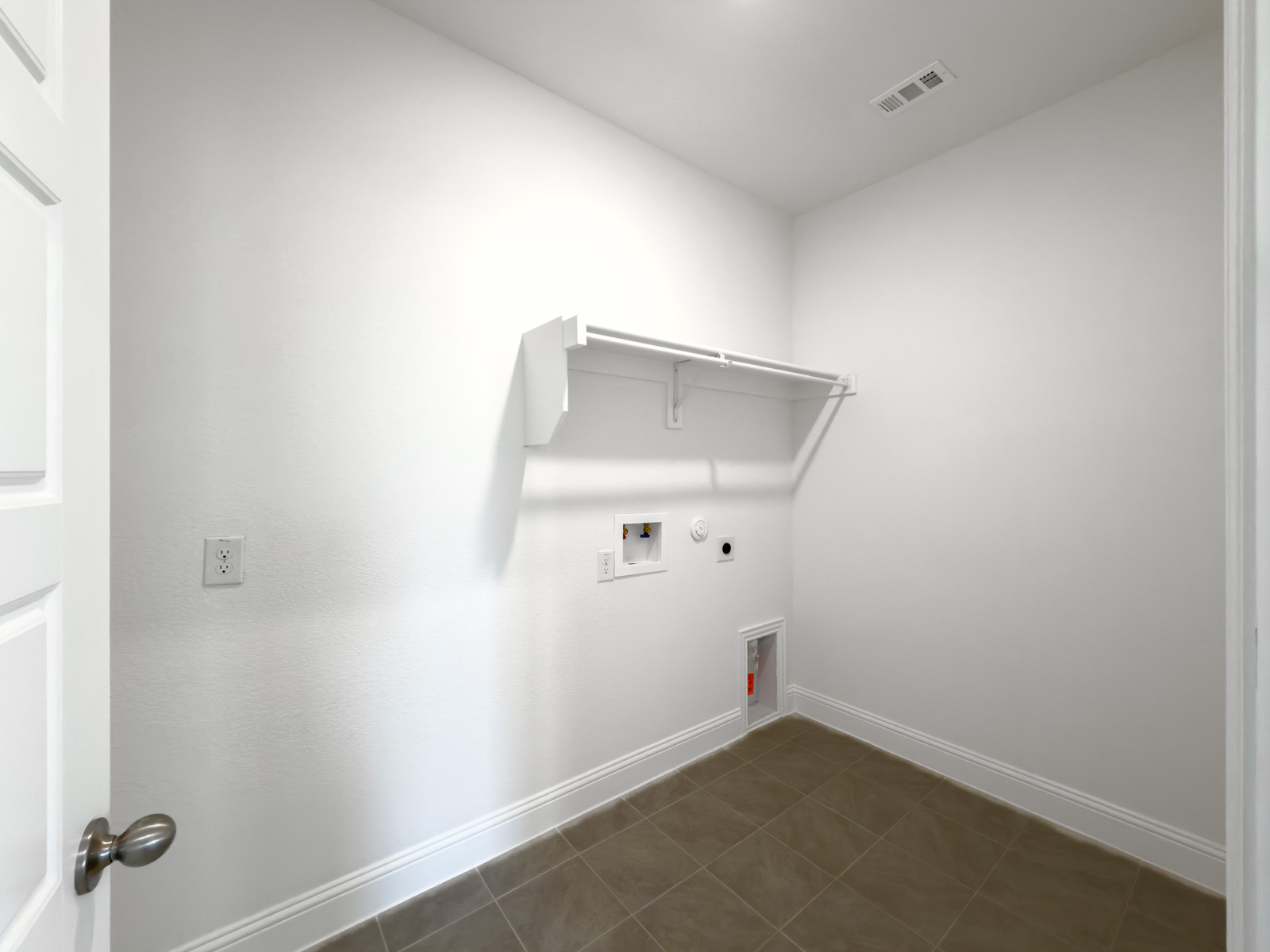 laundry room with tile flooring and storage shelf