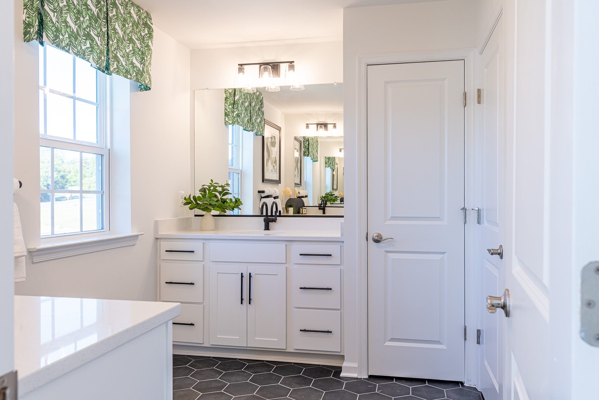primary bath with white vanities and designer tile flooring
