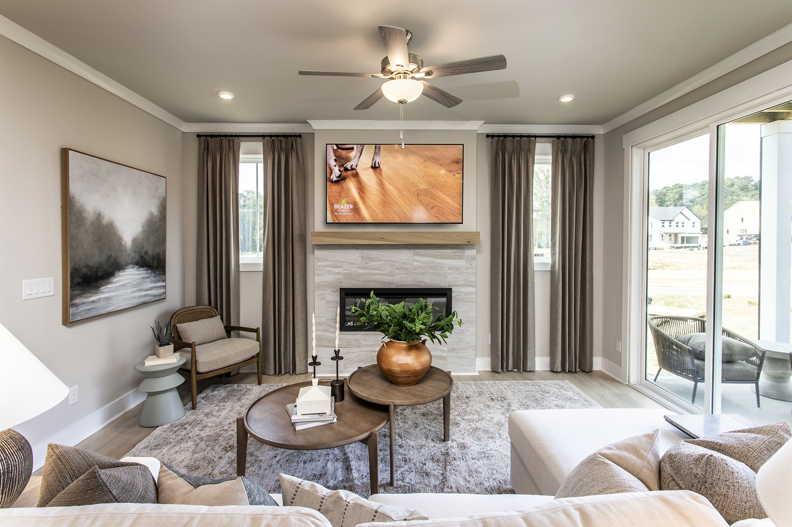 great room with electric fireplace and tri-slide glass doors leading to covered patio