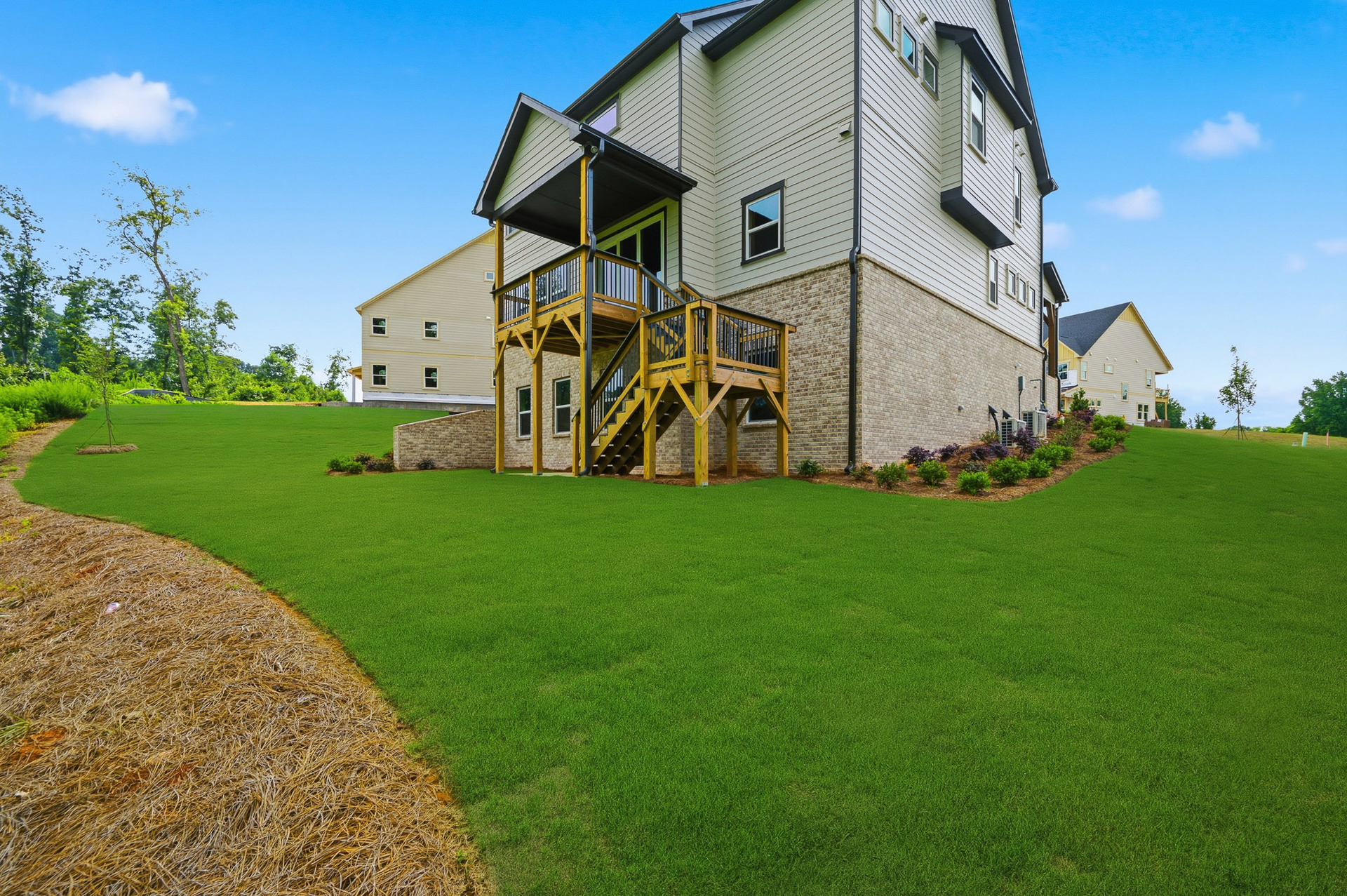 back of 2-story home on a basement with lush green landscaping
