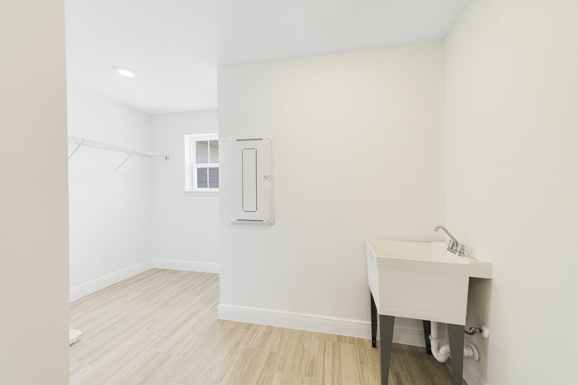room with oversized sink, single window and storage racks