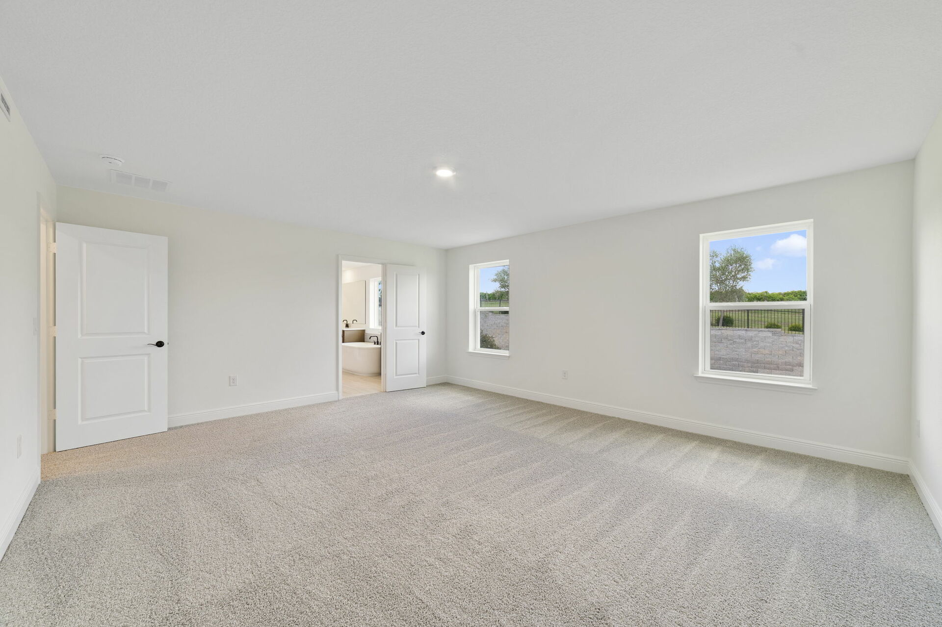 carpet throughout with multiple windows and access to the primary bathroom