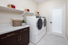 laundry room with neutral floors and storage