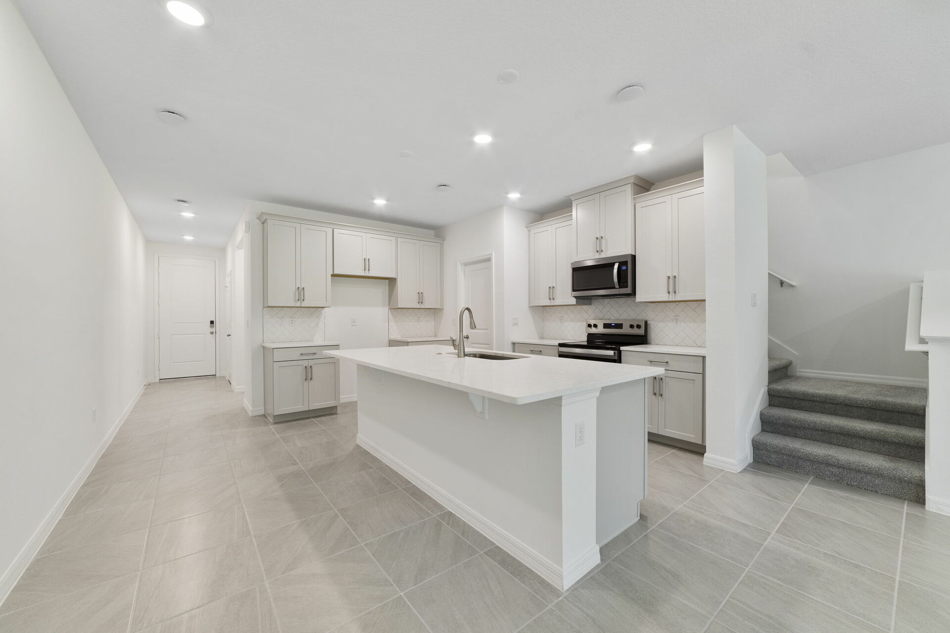 center island kitchen with view of great room and access to the stairs