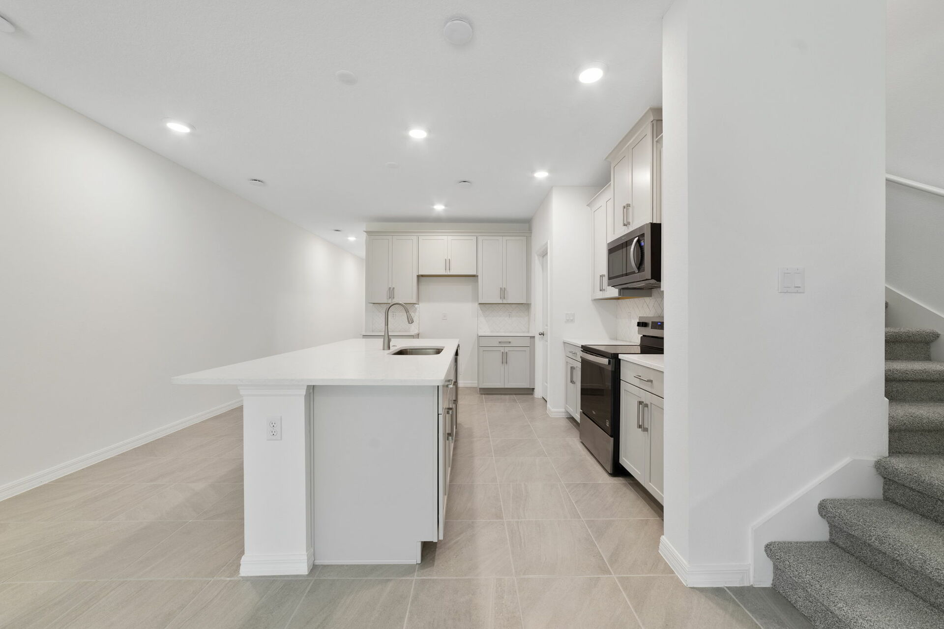 center island kitchen with view of great room and access to the stairs
