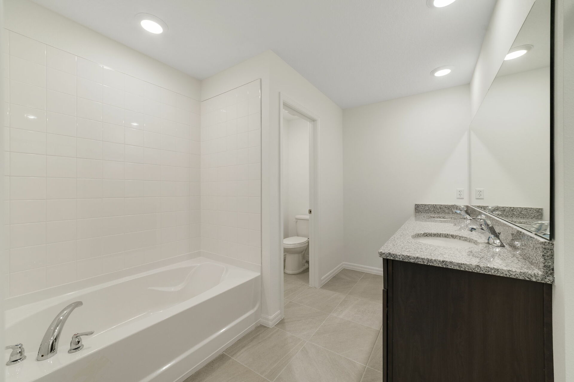 dual sink vanity with water closet, shower, and tub