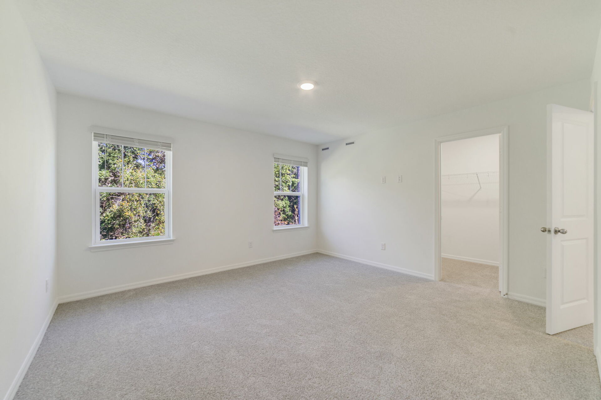 primary bedroom with view of multiple window and access to primary bathroom