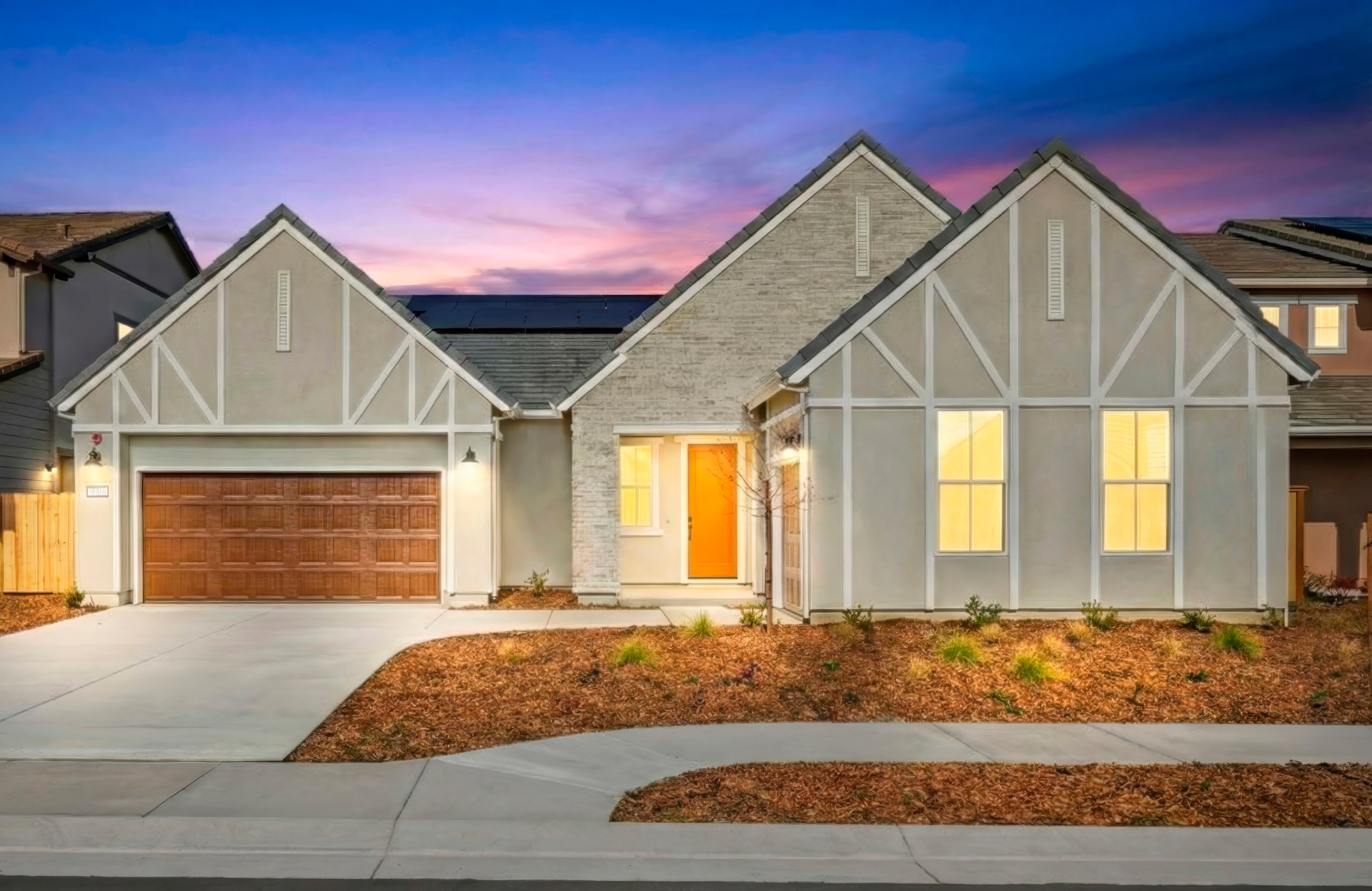 front exterior of light gray single-story home with brown garage at dusk