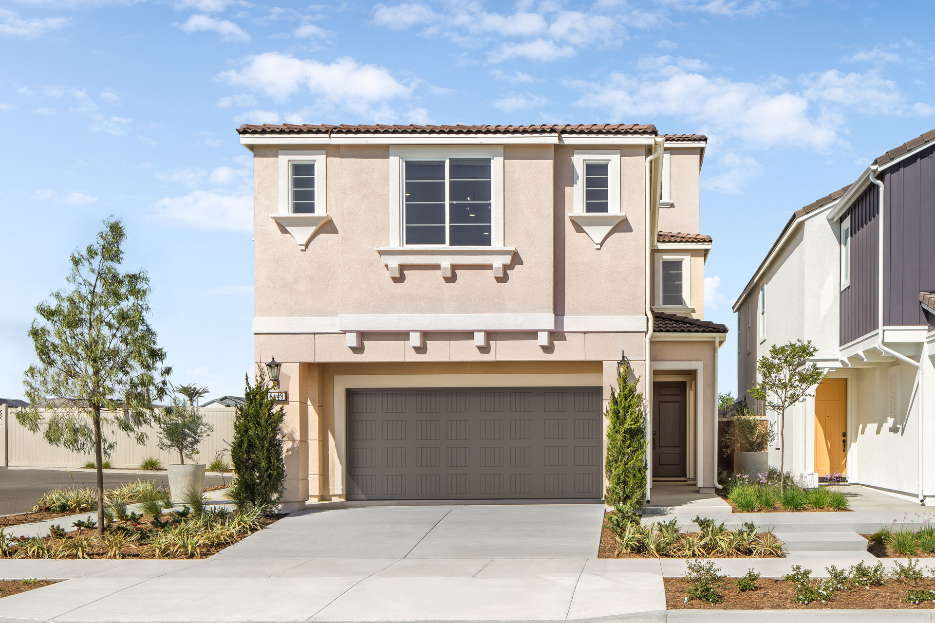 exterior of two-story home with neutral paint and desert landscaping