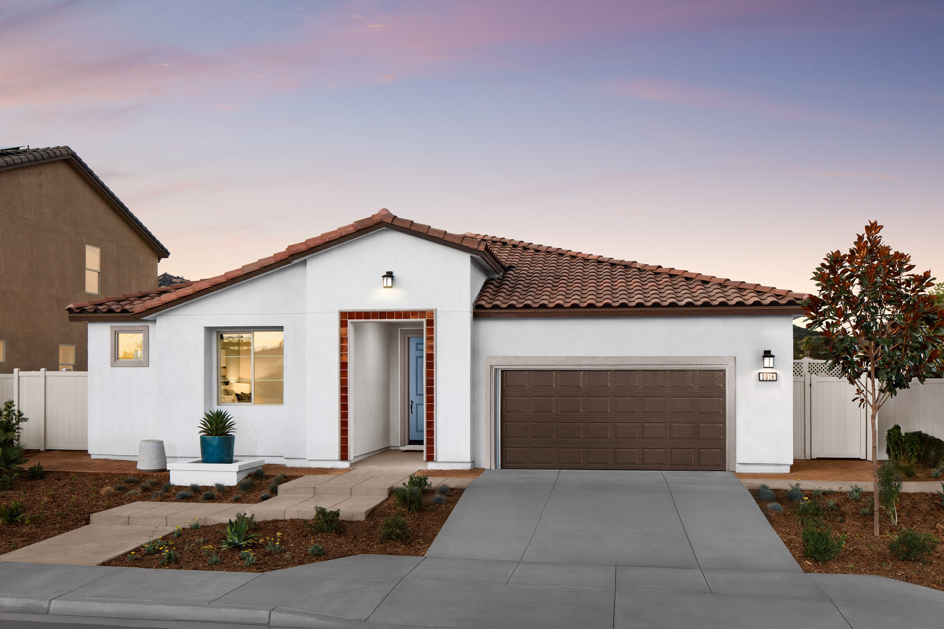 one-story exterior with a brown windowless garage and a red tile trim on the front entry