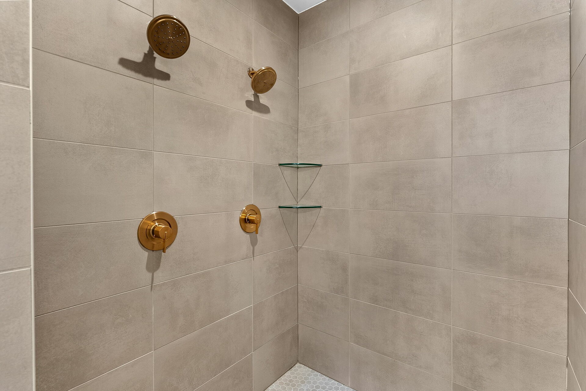 walk in shower with gold hardware and tile