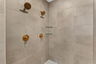 walk in shower with gold hardware and tile