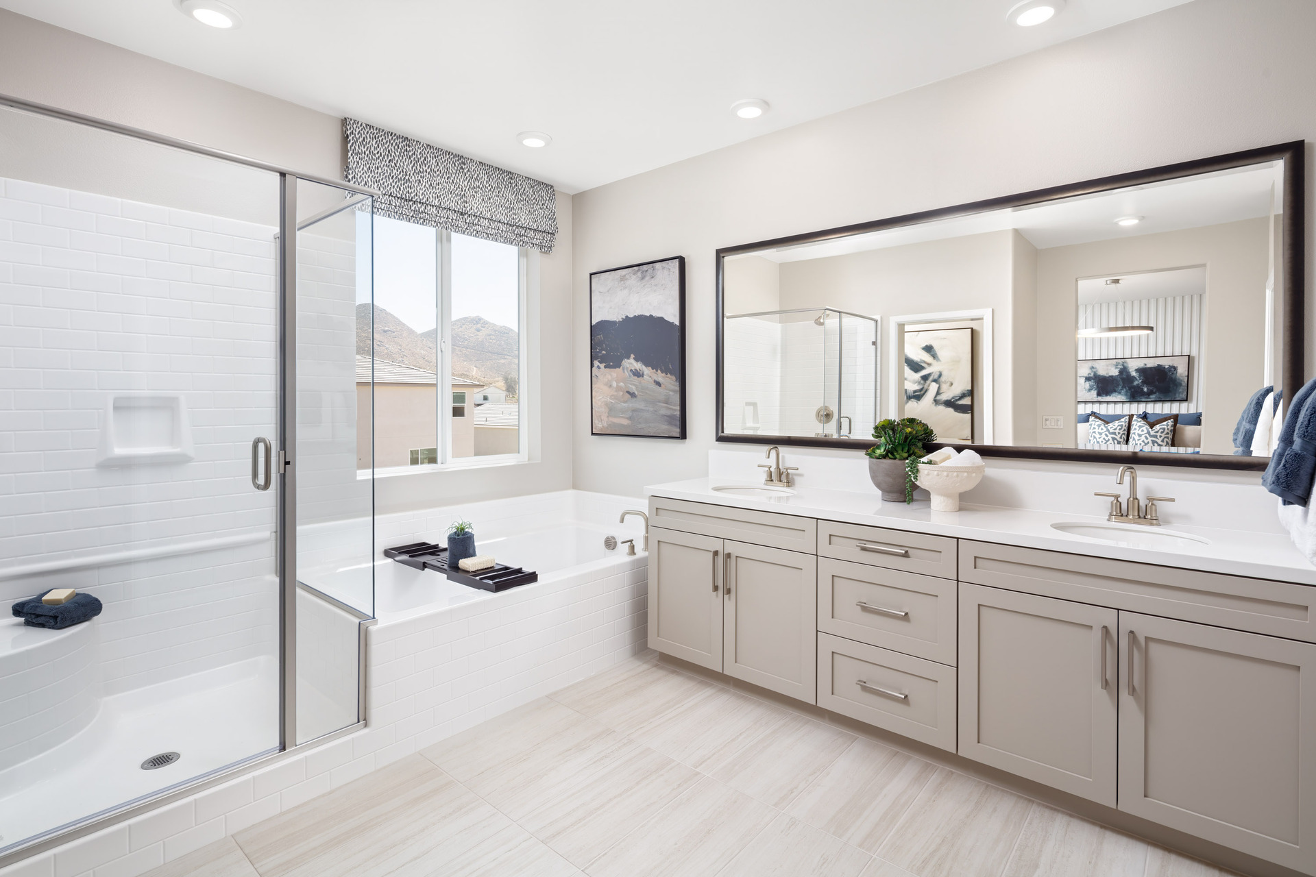 primary bathroom with white countertops and large window